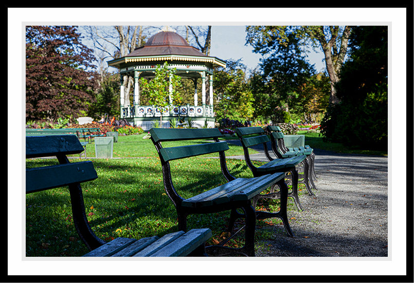 A few benches and a gazebo sit deserted in a park.